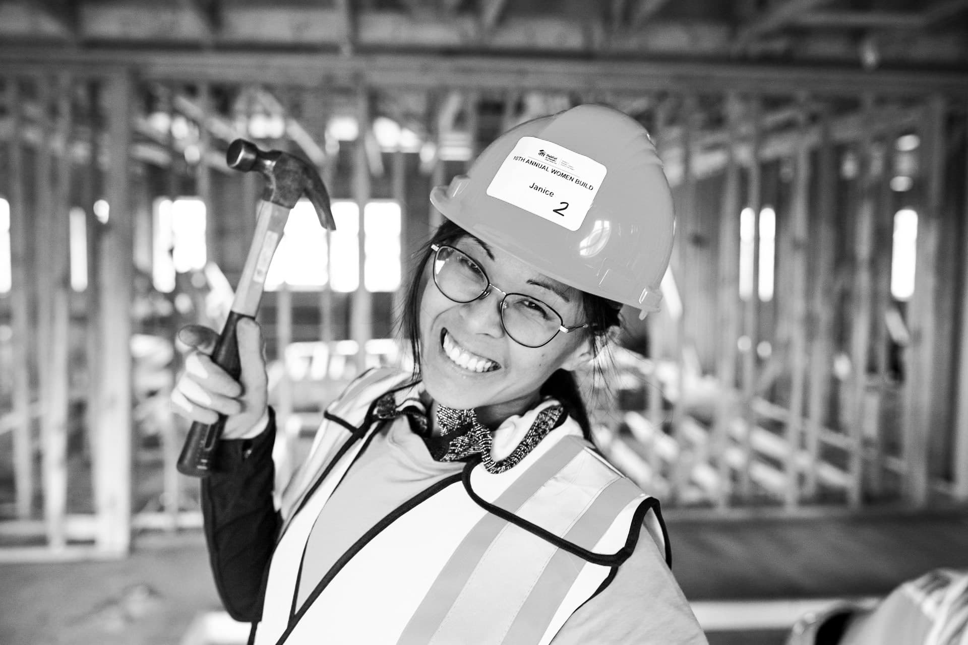 Trades portrait of female builder with hammer at construction framing